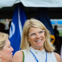 Two guests smiling in front of the American flag and the Grand Valley flag at the Jamie Hosford Football Center dedication.